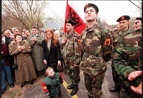 Il Kosovan Liberation Army. In apertura Hillary Clinton con Obama e, sullo sfondo, il Bondsteel Camp in Kosovo